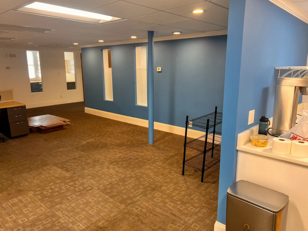 Renovated office interior with blue walls, support columns, and carpet tile