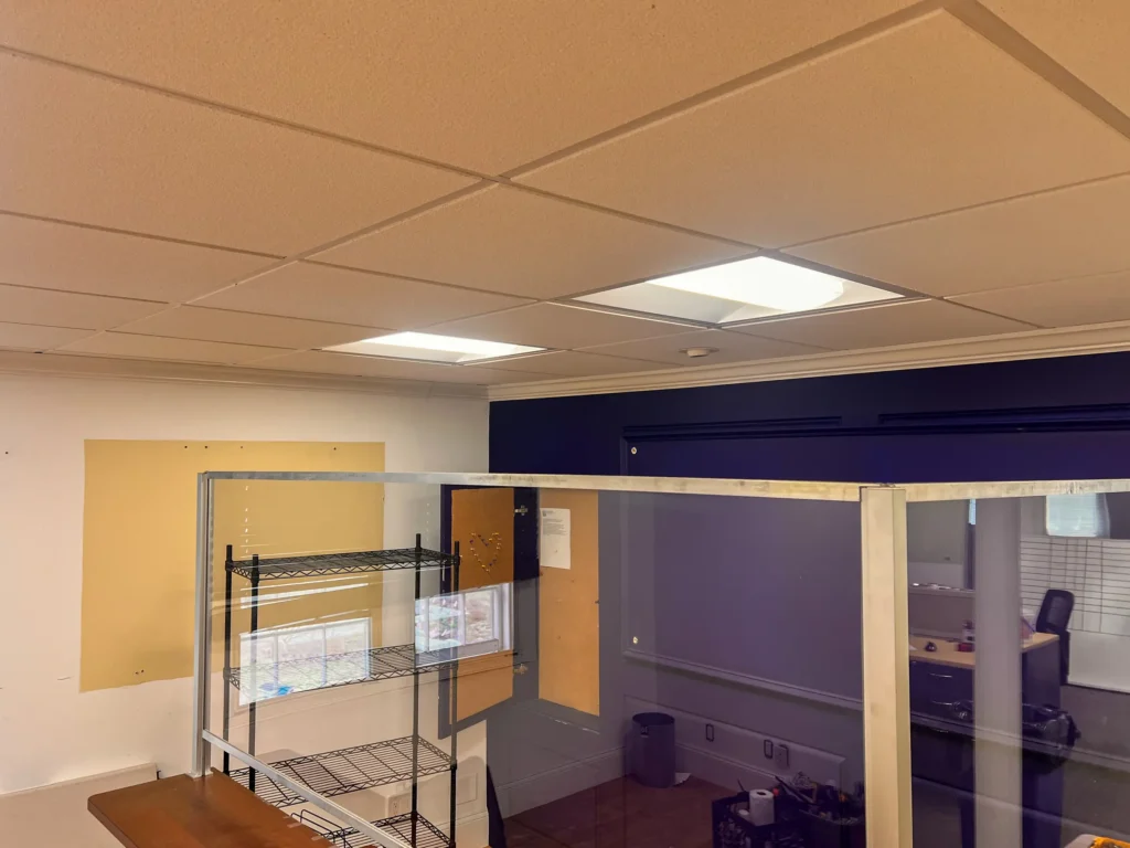 Commercial interior with glass partition, shelving, and refreshed ceiling