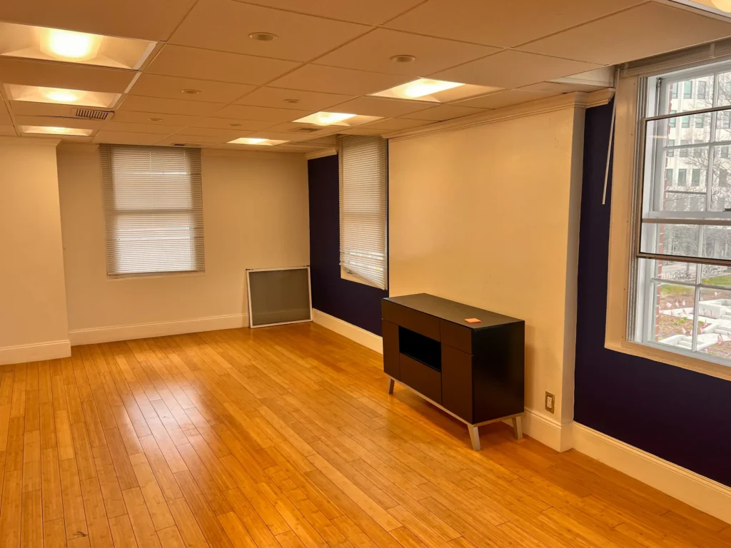 Finished room with hardwood floors, purple accent wall, and large windows